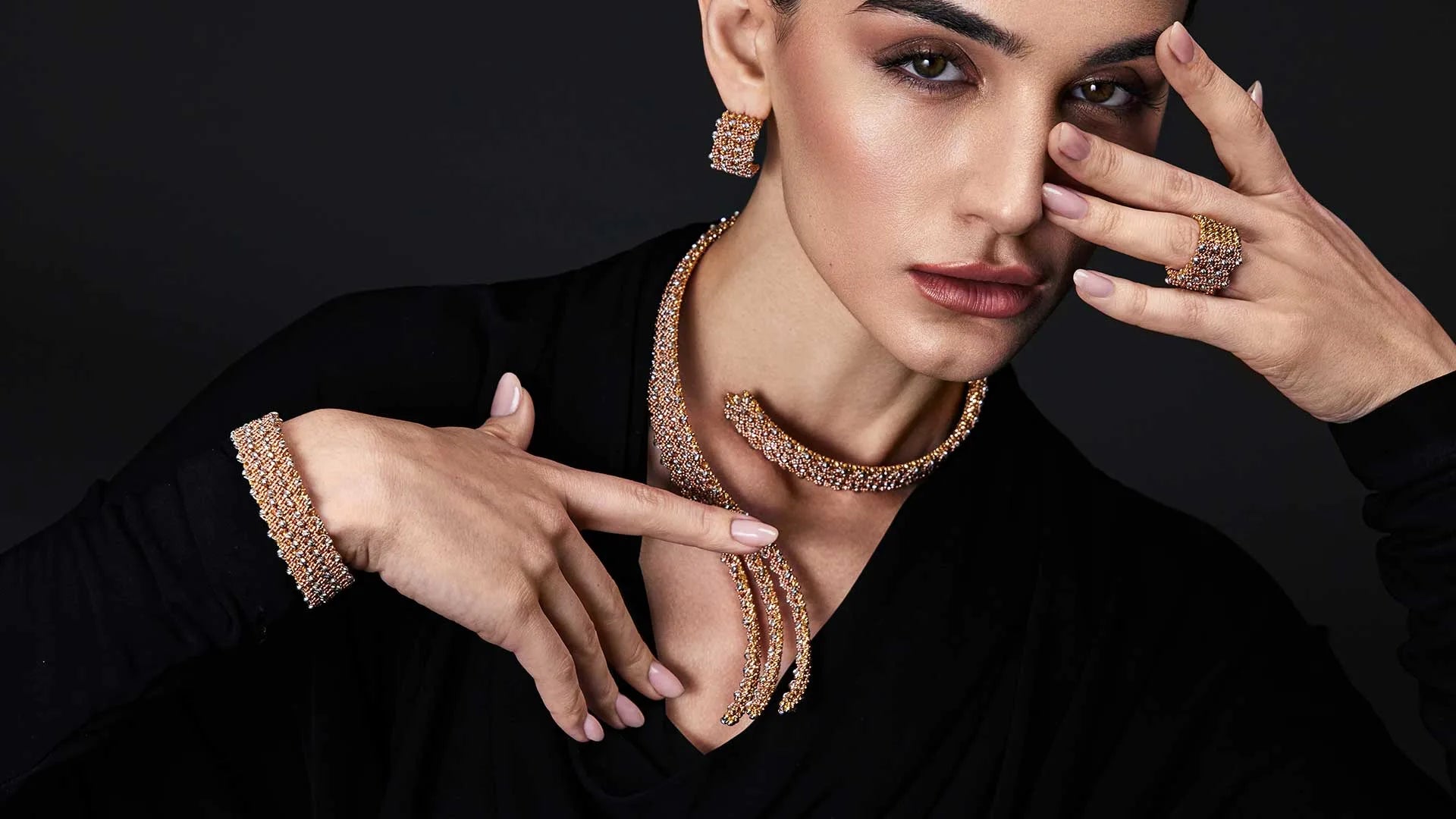 Woman wearing gold jewelry against a black background
